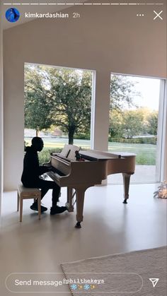 a person sitting at a piano in front of large windows