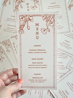 a person holding up a menu in front of many other cards with flowers on them