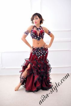 a woman in a red and black belly dance outfit with her hands on her hips