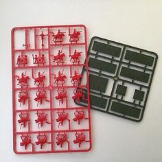 two plastic trays with small red and black toy soldiers on them next to each other