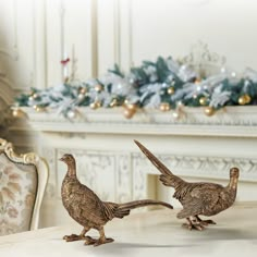 two birds standing next to each other in front of a fire place with christmas decorations