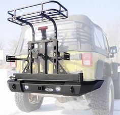 a yellow truck with a rack attached to it's rear bumper in the snow