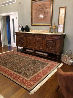 a large rug is on the floor in front of a wooden cabinet and mirror with two framed pictures above it