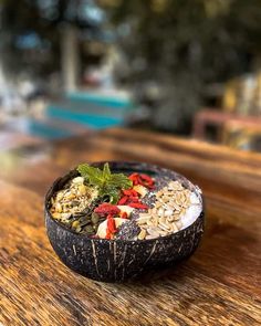 a wooden table topped with a bowl filled with granola and fruit on top of it