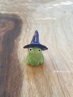 a small ceramic figurine with a hat on it's head sitting on a wooden surface