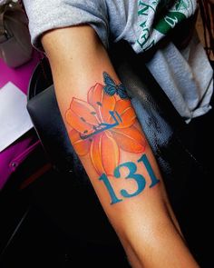 a woman's arm with a flower tattoo on it and the number thirteen in blue