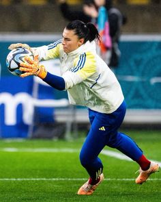 a female soccer goalie in action on the field with her gloved hand out