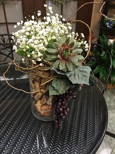 a vase filled with flowers and rocks on top of a table next to some plants