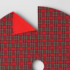 a red and black plaid cloth with a hole in the middle on a white surface