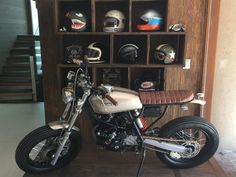 a motorcycle parked in front of a wooden shelf with helmets on it's back