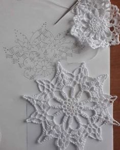 some crocheted snowflakes are laying on top of a piece of paper