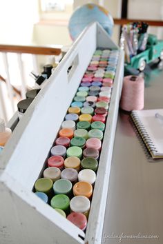 an open box filled with lots of different colored buttons and thread on top of a table