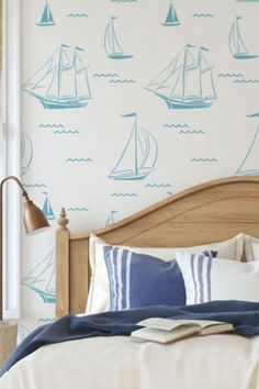 a bed room with a neatly made bed and a wallpapered background that has sailboats on it