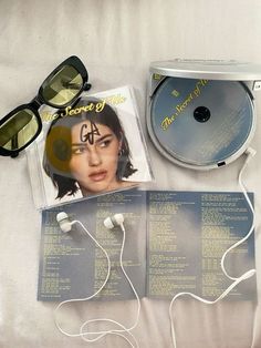 a cd and sunglasses on a bed next to each other