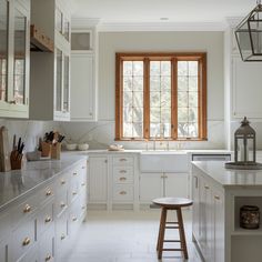 a large kitchen with white cabinets and counter tops, an island in front of the window