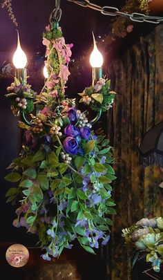 a chandelier with flowers and candles hanging from it