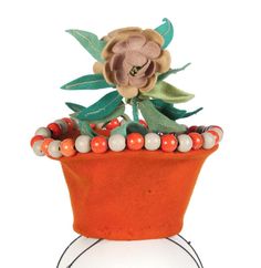 an orange flower pot with beads and leaves