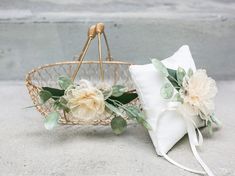 a basket with flowers on it next to a white pillow and some other items in the background