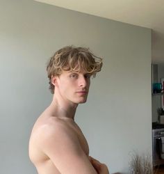 a shirtless young man standing in front of a kitchen counter with his hands on his hips