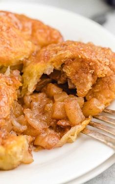 a white plate topped with fried food and a fork on top of it, next to a piece of pie