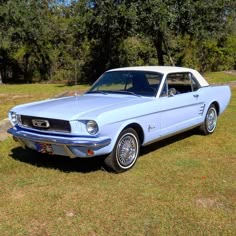 a light blue mustang parked in the grass