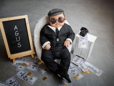 a baby doll is sitting on the floor next to money and a sign that says aggus