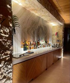 a long counter with bottles on it in a room that has wood paneling and stone walls