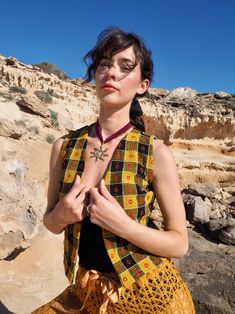 Introducing our Small Cropped Waistcoat, a standout piece from Vagabond Ibiza crafted from upcycled vintage textiles. This waistcoat combines mustard yellow, black, and red hues in a unique pattern, blending wool and cotton for a soft yet structured feel. Designed for the modern bohemian, it offers a fresh take on sustainable fashion by repurposing vintage materials. Perfect for layering over dresses or pairing with high-waisted jeans, this waistcoat is a versatile addition to any wardrobe. Celebrate sustainability and timeless style with this one-of-a-kind piece. Each waistcoat is handmade in our studio in Ibiza, produced in small batches to ensure exclusivity and attention to detail. Crafted from sustainable recycled fabric, every piece is unique, reflecting the individuality and spirit Cropped Waistcoat, Indian Sari Dress, Sari Dress, Kimono Sweater, Retro Girls, Vintage Glamour, Modern Bohemian, Vintage Textiles, Upcycled Vintage