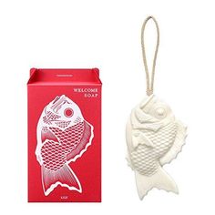 a white fish ornament sitting next to a red box with a welcome sign on it