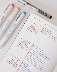 three pens and a crossword puzzle on top of an open notebook