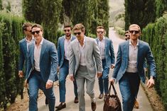 a group of men walking down a street next to each other wearing suits and sunglasses