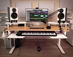 a desk with a keyboard, monitor and speakers on it in front of sound equipment