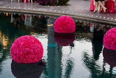 pink balls are floating in the water at a wedding reception with people sitting around them