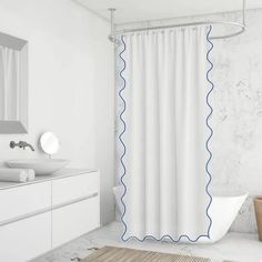 a white bathroom with blue trim on the shower curtain and bathtub next to it