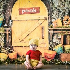 a baby sitting on the floor in front of a wooden door with poth written on it