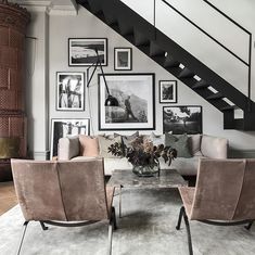 a living room filled with furniture and framed pictures on the wall above it's stairs