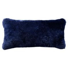 a dark blue pillow with fluffy fur on the front and back, sitting against a white background