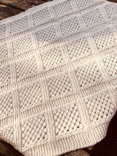 a white crocheted blanket sitting on top of a wooden table next to scissors