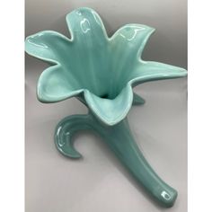 a green flower shaped vase sitting on top of a table