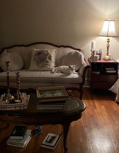 a living room filled with furniture and a lamp on top of a coffee table in front of a window