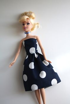 a doll with blonde hair wearing a black and white polka dot dress