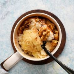 a bowl filled with food sitting on top of a table next to two spoons