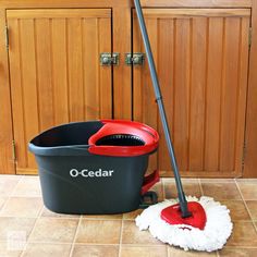 a red and black mop sitting on top of a floor next to a bucket