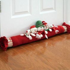 a group of stuffed snowmen sitting on top of a red blanket in front of a door