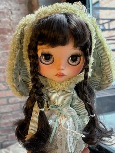 a doll with long hair wearing a dress and bonnet on top of it's head