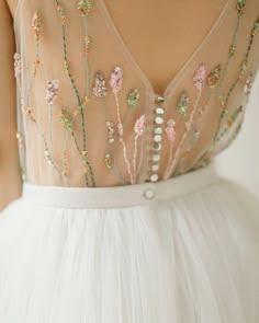 the back of a woman's dress with beaded flowers and pearls on it