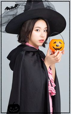 a woman in a witch costume holding an orange jack - o'- lantern and wearing a black hat