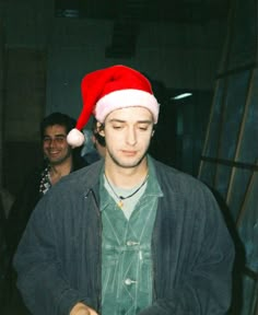 a young man wearing a santa hat is cutting food