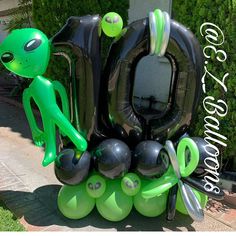 an inflatable balloon sculpture is sitting on the sidewalk with scissors and balls around it