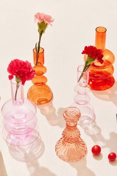 several vases with flowers in them sitting on a table next to other glassware